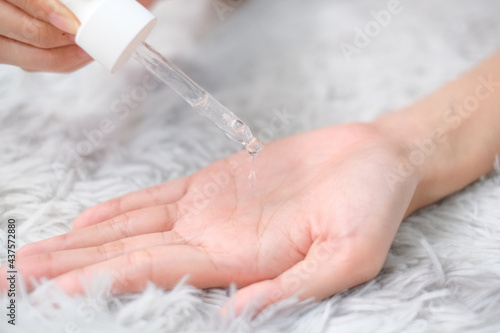 Woman hands apply cosmetic serum from bottle using pipette on carpet background, Health care concept.