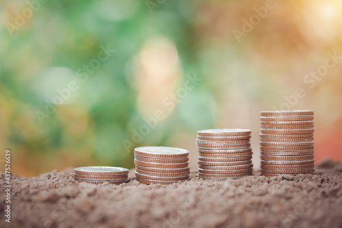 Money stacking of coins on soil, saving money concept, home, loan, education and plan for future isolated on bokeh background.