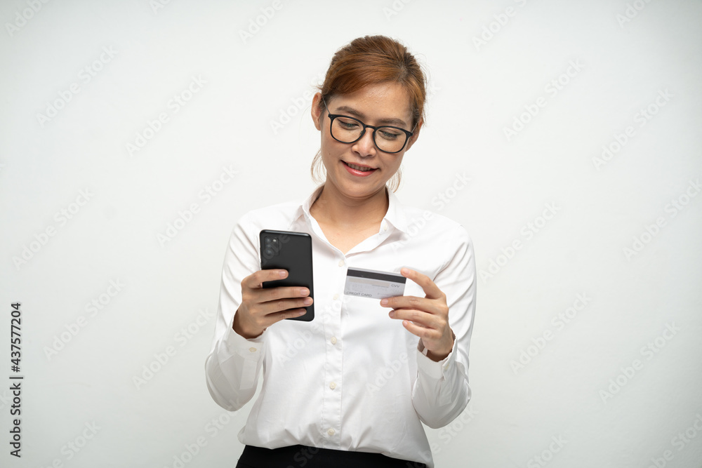 A beautiful office woman wearing a white shirt is using a smartphone and credit card to pay for products.Online shopping. A beautiful office woman wearing a white shirt is using a smartphone and credit card to pay for products.Online shopping.