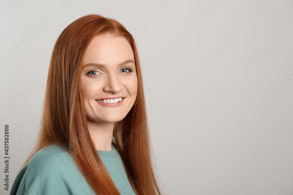 Candid portrait of happy young woman with charming smile and gorgeous red hair on light background, space for text Candid portrait of happy young woman with charming smile and gorgeous red hair on light background, space for text