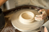female hands make dishes from clay on a potter's wheel