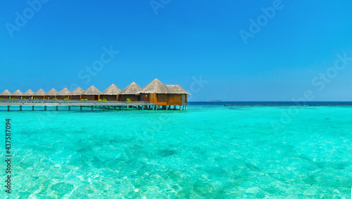 Amazing wide panorama of tropical Maldives island on a sunny day. Exotic vivid beach background with blue turquoise lagoon and palm trees. Luxurious holiday and romantic honeymoon destination.