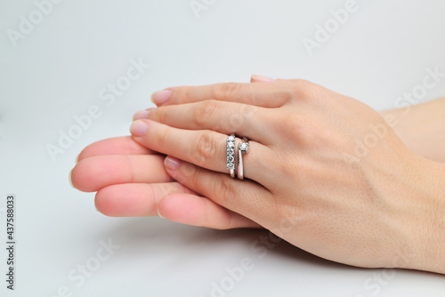 Female hand holding a white gold ring with diamonds on white background isolation. Holding the engagement ring. Hand of a caucasian adult woman with a diamond engagement ring. 
