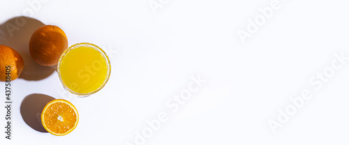 glass with fresh juice and oranges on a light background. Top view, flat lay. Banner