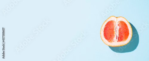 cut half of a grapefruit on a blue background. Top view, flat lay. Banner