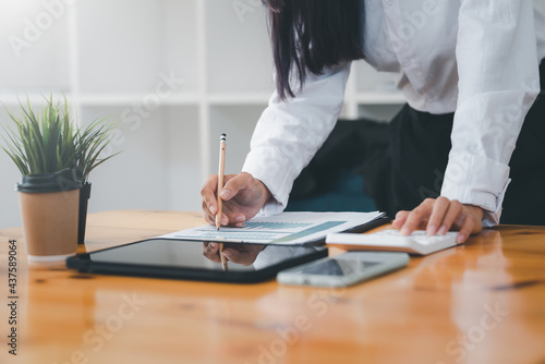 Image of a businesswoman working on a graph calculator and tablet placed on a table hand holding a pencil at the office accounting concept.