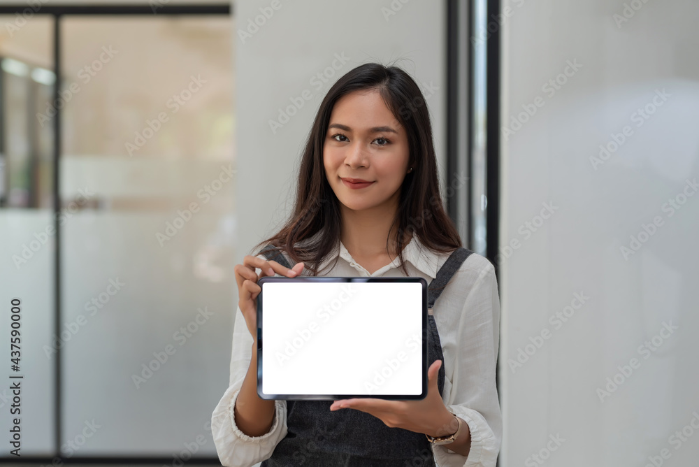 Asian businesswoman standing holding tablet blank white screen. Looking at the camera.
