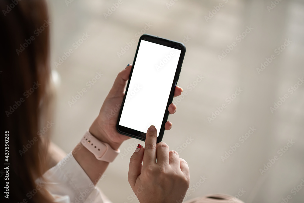 Image of a woman hand sitting in a chair at the office using blank white screen smartphone. Mock up. Image of a woman hand sitting in a chair at the office using blank white screen smartphone. Mock up.