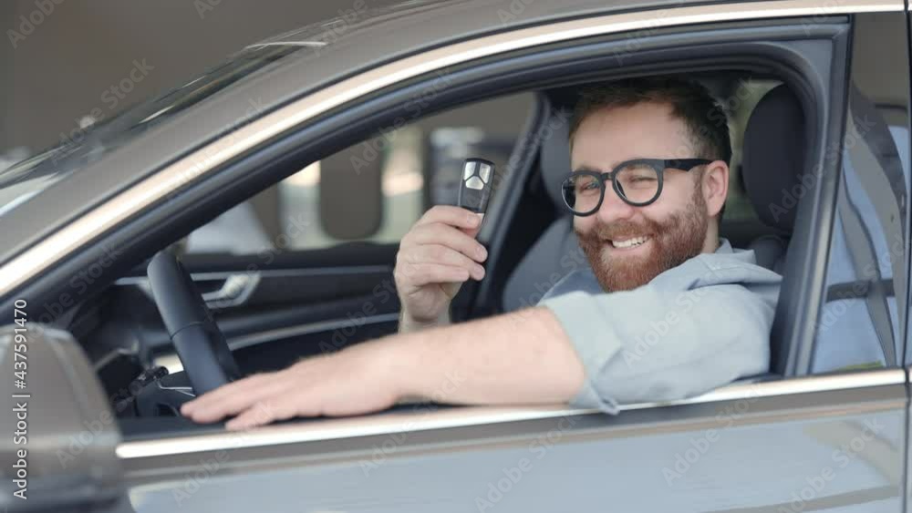 Cheerful guy with keys in hands sitting inside his new auto Cheerful guy with keys in hands sitting inside his new auto