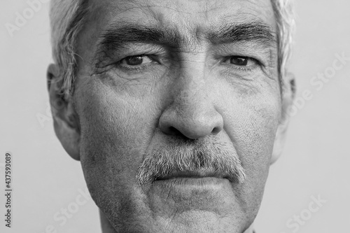 the face of an elderly man is monochrome close-up. portrait of a mature male pensioner aged 60 with a mustache.