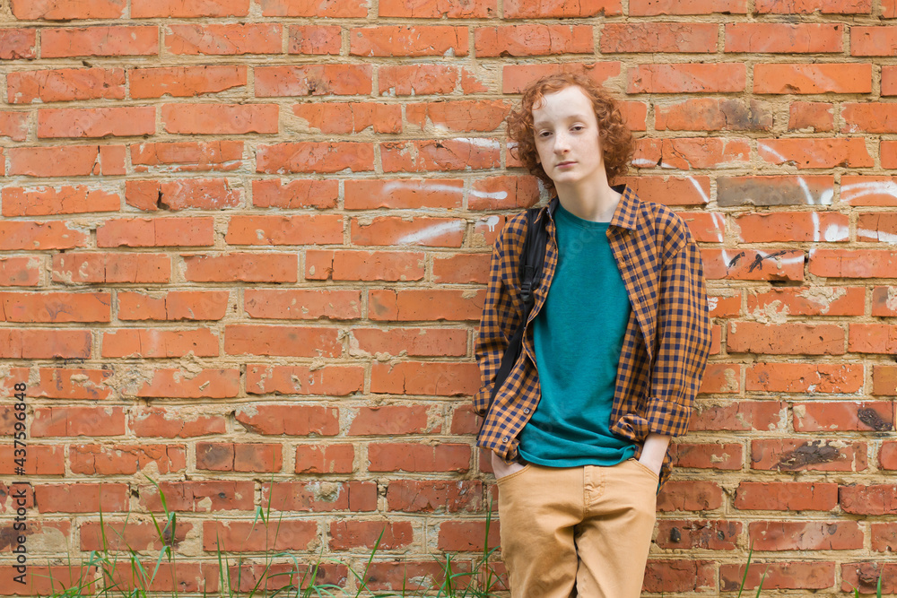 Empty space for text. Portrait of a young man against a red brick wall. Empty space for text. Portrait of a young man against a red brick wall.