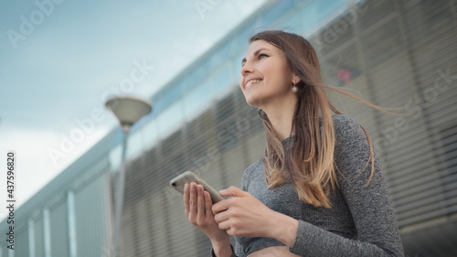 Fitness, sport and technology concept - happy smiling woman running outdoors. Close-up Of A Young Beautiful Sports Fitness Girl Holding A Smartphone In The Hands. Phone conversation during training