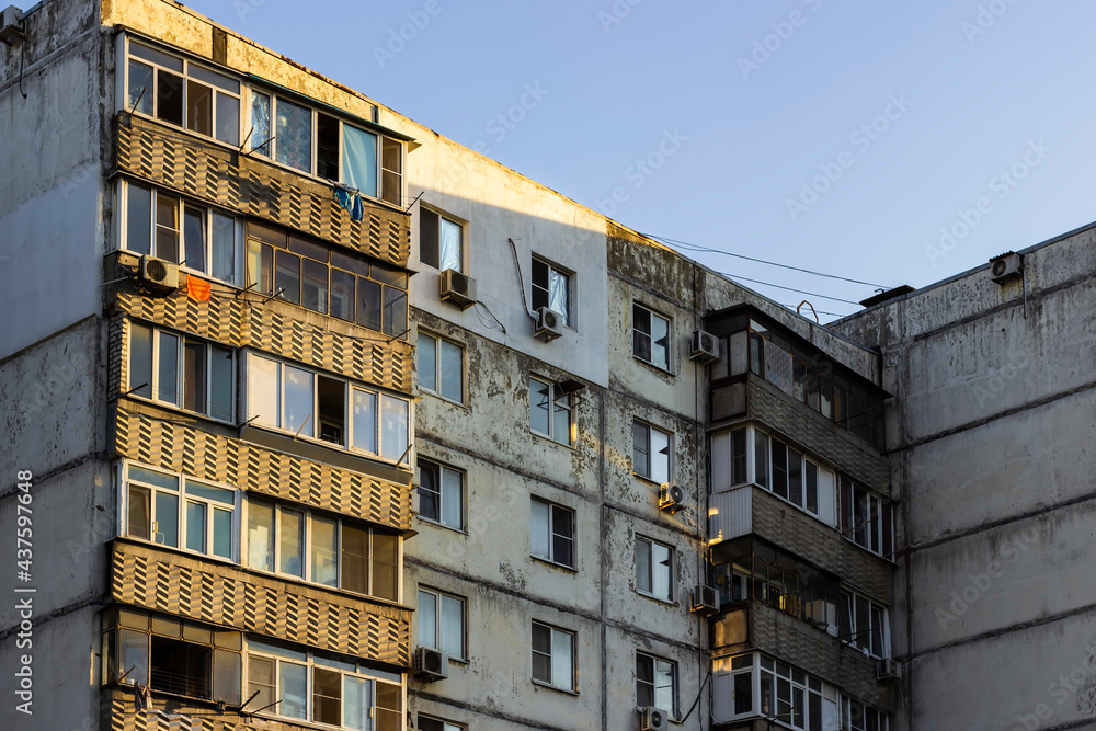 Multi-storey panel Soviet residential building in summer. Yellow rays of light on the walls of a Soviet panel high-rise building.