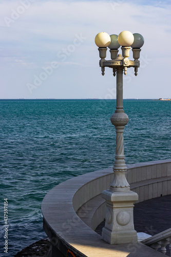 Granite carved lantern on the waterfront on the background of the sea.