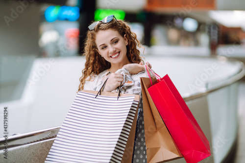 Young woman after shopping with shopping bags walking in the mall. Consumerism, sale, purchases, shopping, lifestyle concept.