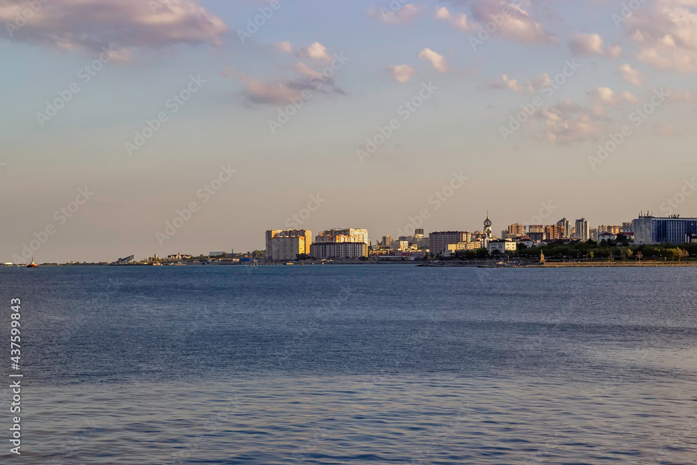 Coastline of a modern coastal town at sunset. Church and high-rise residential buildings on the seashore. Vertical orientation. Portrait orientation.