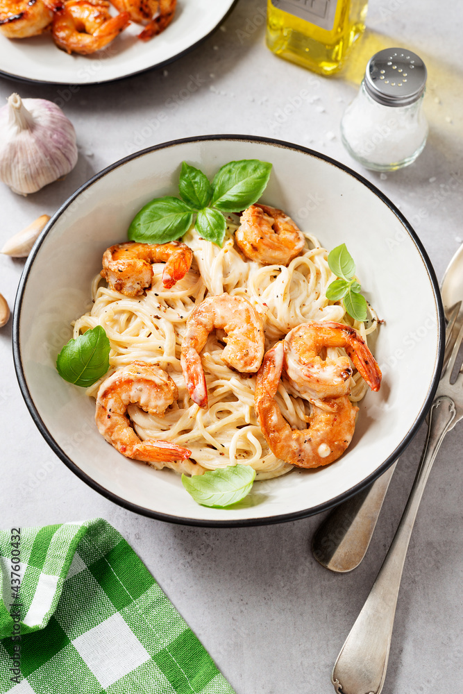 Pasta spaghetti with grilled shrimp and creamy alfredo sauce served with fresh basil leaves. Light gray background Pasta spaghetti with grilled shrimp and creamy alfredo sauce served with fresh basil leaves. Light gray background