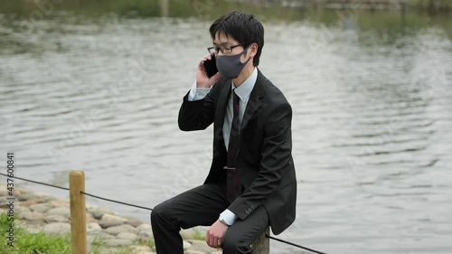 コロナ禍に川原でビジネスパーソンがマスクしてスマホで電話2