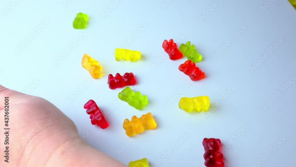 red, orange, yellow gelatin candies, drug-filled gelatin bears falling on the table from above, bouncing, scattering, slow motion, concept of children's sweets, drugs red, orange, yellow gelatin candies, drug-filled gelatin bears falling on the table from above, bouncing, scattering, slow motion, concept of children's sweets, drugs
