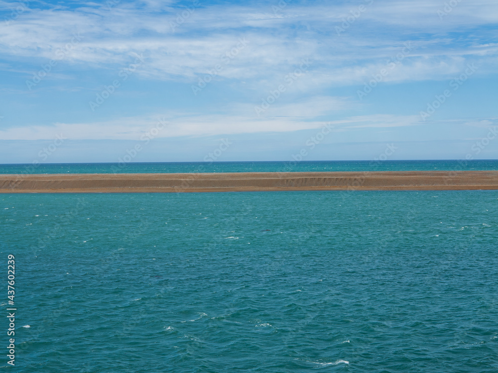 Obraz premium Minimalist Landscape with Blue Sea, Line of Sandy Beach and Sunny Sky. Sea Horizon. Calm Water Surface and Sky with Soft Clouds. 