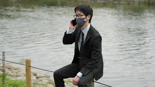 コロナ禍に川原でビジネスパーソンがマスクしてスマホで電話3
