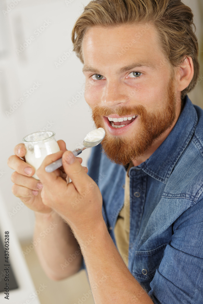 cheerful young asian man eating yogurt for breakfast cheerful young asian man eating yogurt for breakfast