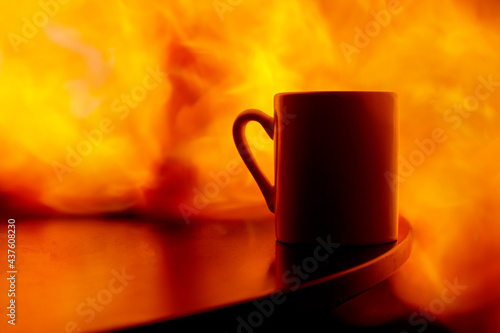 a mug on the table engulfed in flames, a fire in the house. concept