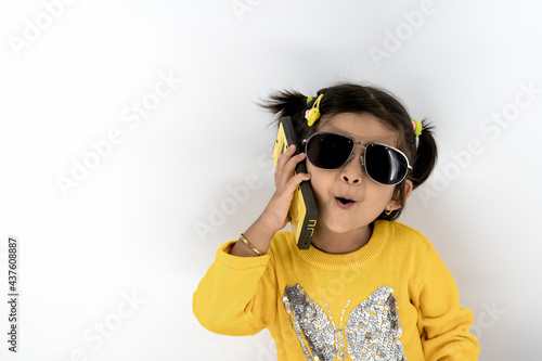 Happy little asian/Indian girl speaking by cell phone with white background background with copy space
