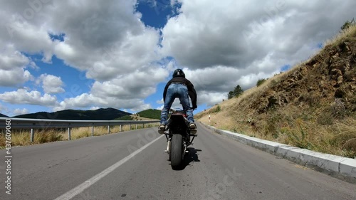 Biker stunt ride biike on mountain rural road and do wheelie on motorcycle photo