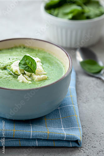 Green cream soup in a blue bowl on a stone grey table