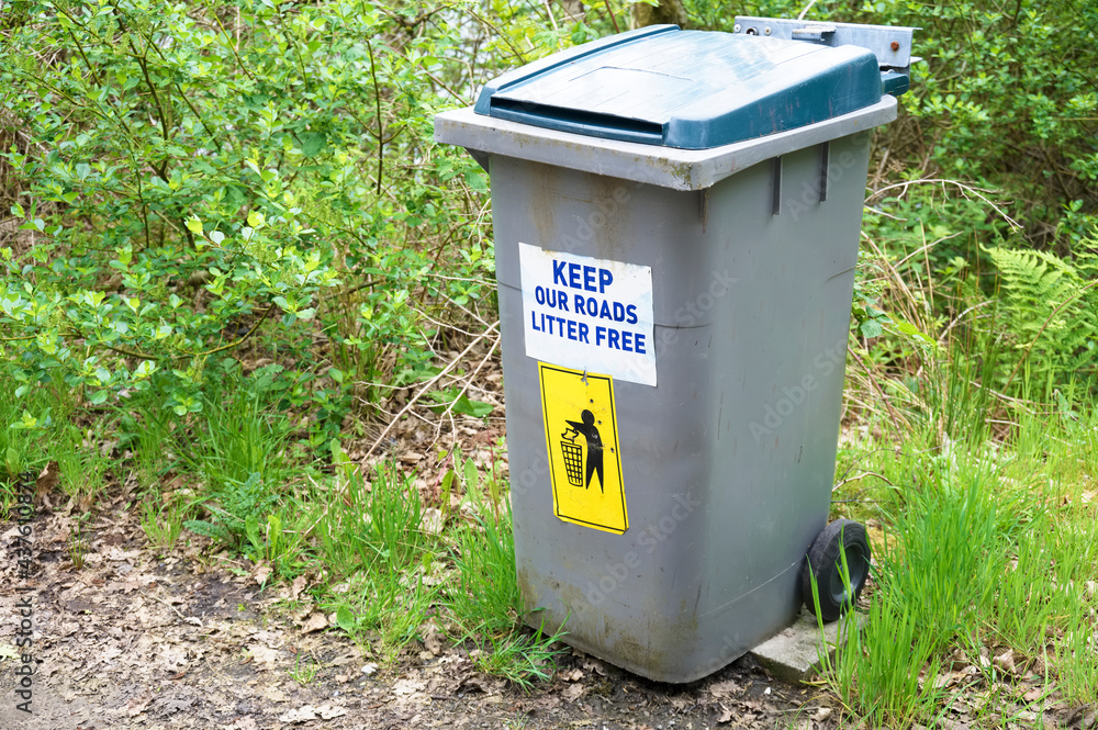 Keep roads litter free sign at roadside on wheelie bin Keep roads litter free sign at roadside on wheelie bin