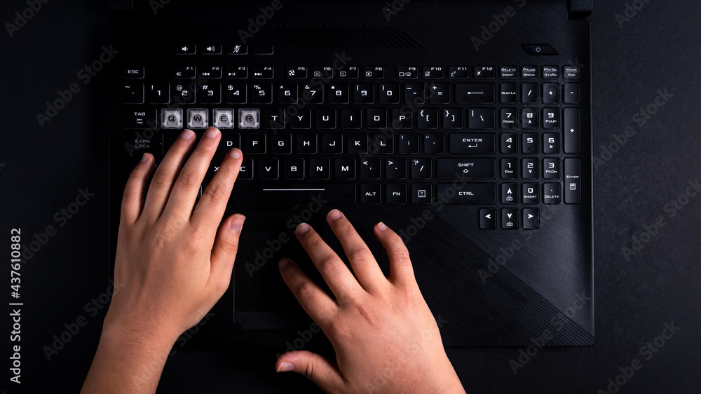 Hands typing on black gamer laptop Hands typing on black gamer laptop