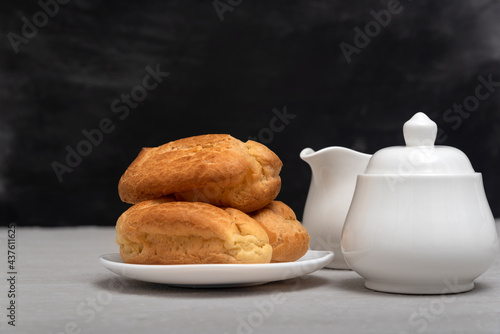 Slika na platnu Lush homemade eclairs and tea-drinking utensils. French pastries