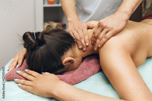 A man is a chiropractor doing a massage to a woman in the neck and trapezius muscles in his office