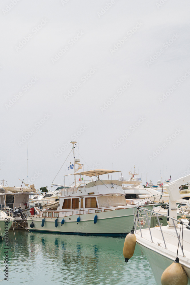 Fototapeta premium Boats parking in harbor. White motorboat at the pier. Sea yacht club. Aegean sea. Athens, Greece. White cloudy sky.