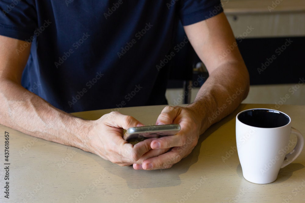 Hands of anonymous man with cellphone on table and coffee cup on side. Stressful lifestyle, busy work, nervous concepts Hands of anonymous man with cellphone on table and coffee cup on side. Stressful lifestyle, busy work, nervous concepts