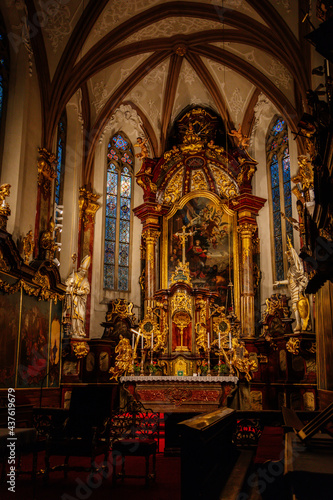 Decorative interior of church St. Henry and St. Kunhuty, gilded ornamented baroque main altar, gothic stained glass windows, marble statues, wood carved benches, Prague, Czech Republic