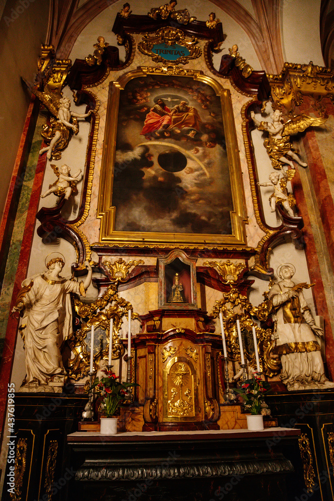 Obraz premium Decorative interior of church St. Henry and St. Kunhuty, gilded ornamented baroque altar, Infant Jesus, tall candles, marble statues, wood carved benches, Prague, Czech Republic