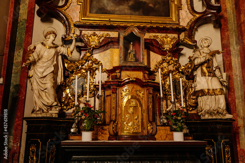 Decorative interior of church St. Henry and St. Kunhuty, gilded ornamented baroque altar, Infant Jesus, tall candles, marble statues, wood carved benches, Prague, Czech Republic