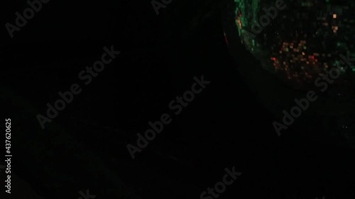 A disco ball with a corner of the frame is periodically illuminated by a spotlight in a loop