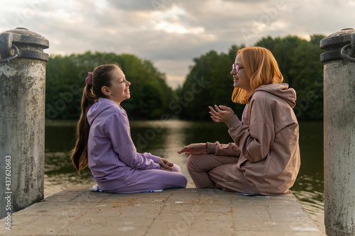 Two teenage girls talking at sunset on lake shore