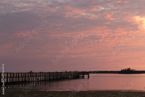 Pink clouds at sunset over a wooden fishing pier jetty