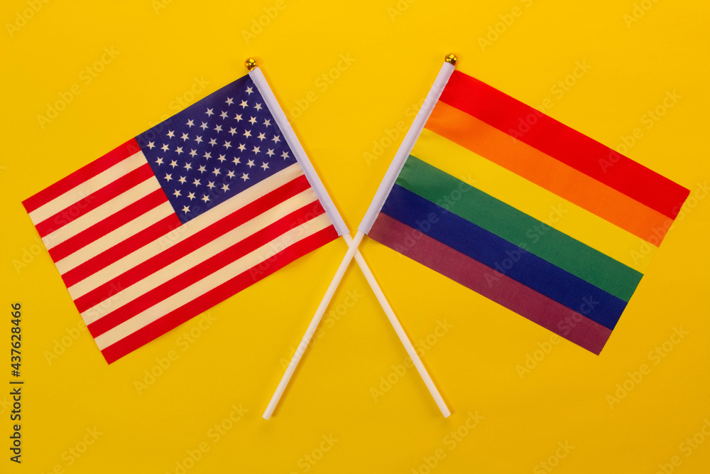 Rainbow flag LGBT and USA flag against the yellow background. LGBT Pride Month. LGBTQ. LGBTQIA. Close Up. Top view Rainbow flag LGBT and USA flag against the yellow background. LGBT Pride Month. LGBTQ. LGBTQIA. Close Up. Top view