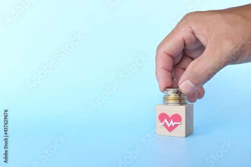 Invest on health over travel, car and material things concept. Human hand putting coins on a healthcare icon.