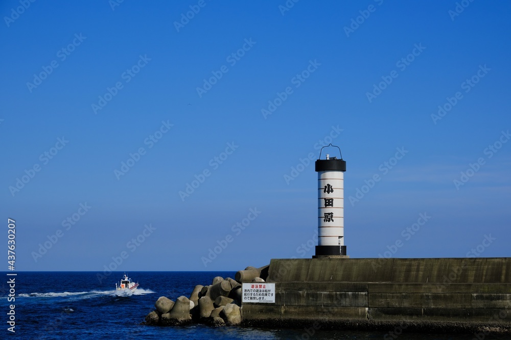 小田原港の提灯型灯台と出港する小型船
