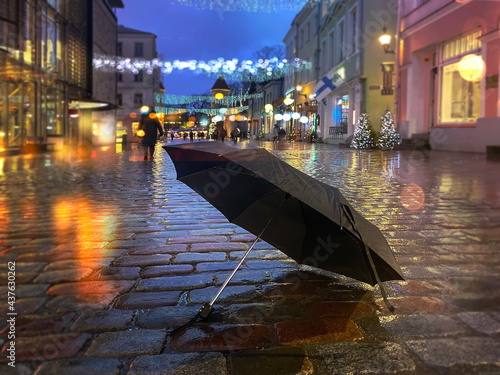 rainy  Christmas black umbrella on wet pavement light blurred decoration people wakl holiday in Tallinn old town Estonia  photo