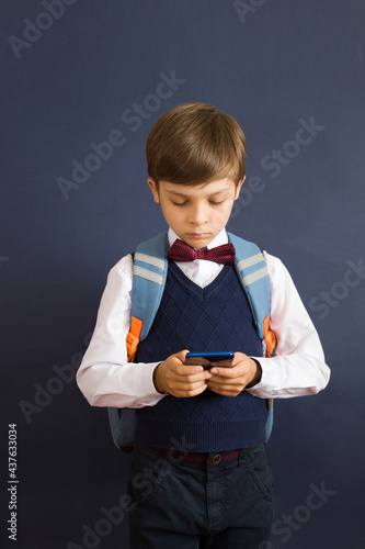 Back to school. Education. A little Schoolboy on dark background with a telefone