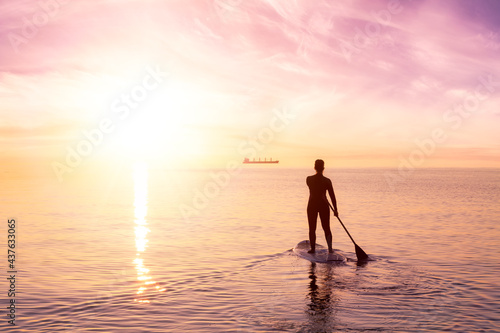 Adventurous woman on a paddle board is paddeling in the Pacific West Coast Ocean. Sunset Sky Art Render. Taken near Spanish Banks, Vancouver, British Columbia, Canada. © edb3_16