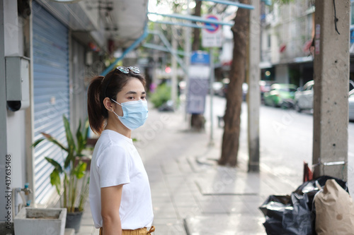 Woman wearing medical face mask during walking in street footpath and night market, prevent coronavirus or Corona Virus Disease (Covid-19). Health, life concept