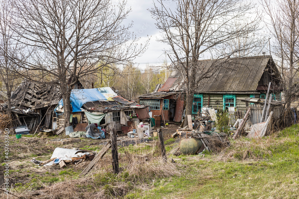 A dilapidated old residential wooden house surrounded by garbage around the house. Poverty in Russia. A dilapidated old residential wooden house surrounded by garbage around the house. Poverty in Russia.